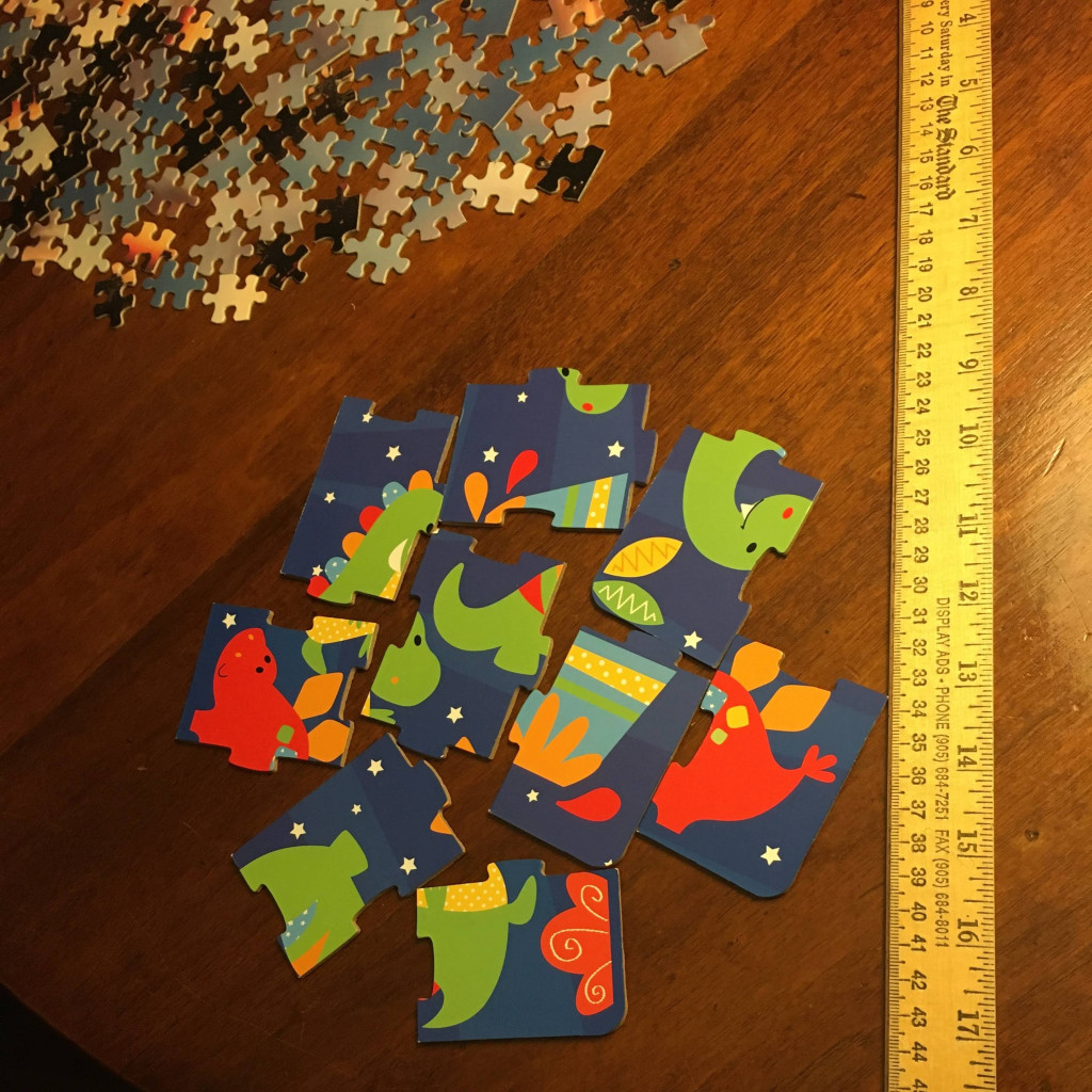 Two unassembled puzzles on a table, one with a few very large pieces and one with many small pieces.